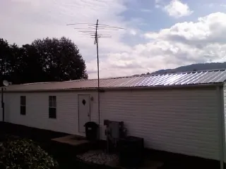 New metal roof on a single wide mobile home with a TV antenna in Jamaica
